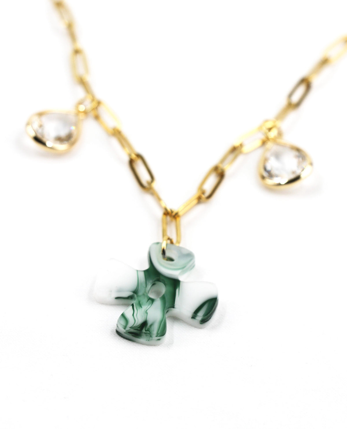 Detalle del Collar Éden dorado con cruz verde y cristales