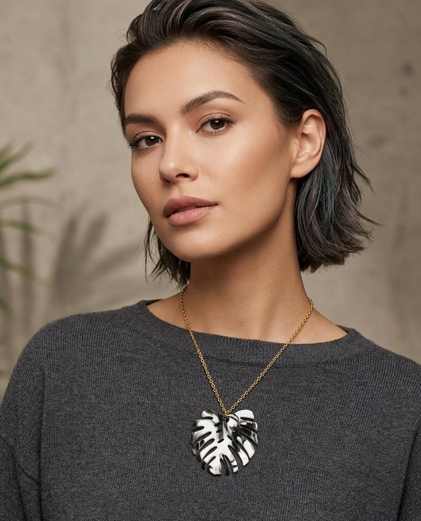 Mujer con Collar Monstera dorado y colgante de hoja blanco y negro ALMIREA