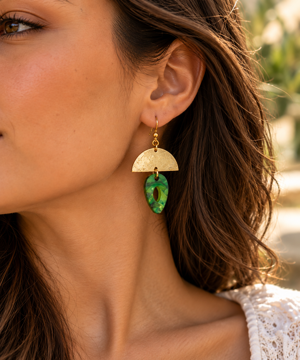 Modelo luciendo pendientes ALMIREA dorados con colgante verde marmolado, diseño geométrico elegante y original para mujer